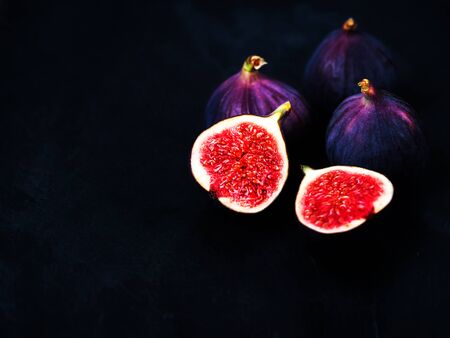 Ripe sweet figs on black background. Healthy Fresh fig fruit, vivid colors.