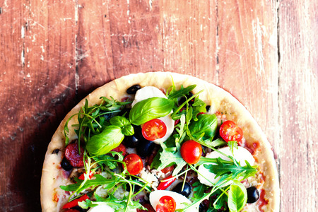 Hot pizza with meat, basil and mozarella cheese on a dark background, top view. Pizza on the rustic...