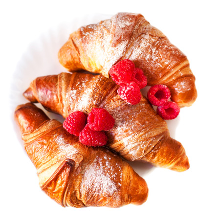 Fresh golden croissants with raspberries close up isolated on white backgroundの写真素材