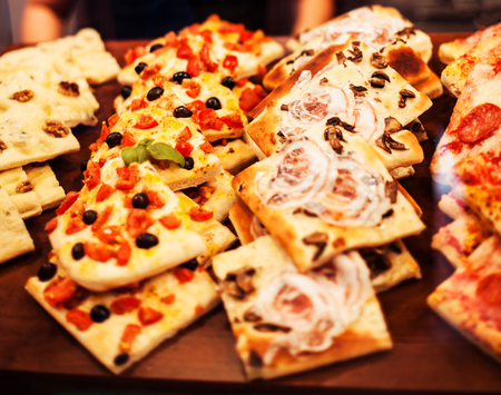 Pizza Slices Take Away - pieces on a stall,  Traditional Italian Focaccia with tomatoes, black olives and cheeseの写真素材