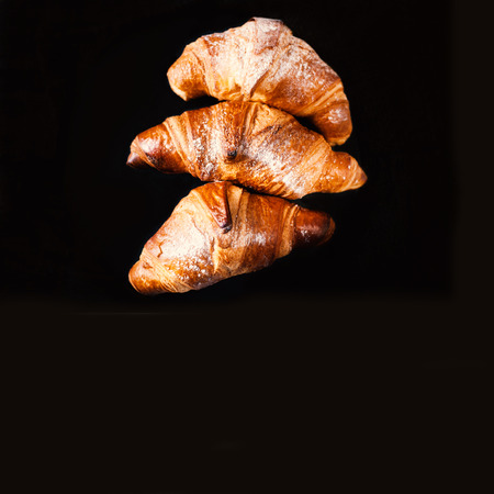 Fresh golden croissants on black background with copyspace for text