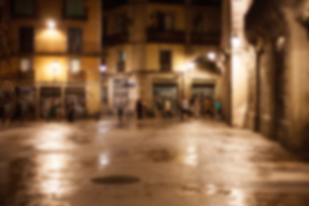 Abstract urban night bokeh defocused background. Old European town concept. Blurry Gothic quarter of Barcelonaの写真素材