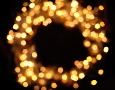 Blur Christmas lights garland on dark  background, holiday card concept. Defocured circle festive lights. Blurred lights in wreath shapeの写真素材