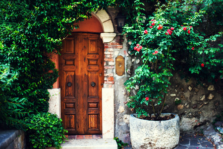 Beautiful garden with old antique door, flowers and ivy. Vintage European cute entrance in a houseの写真素材