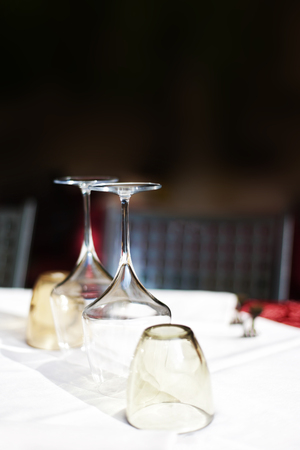 Empty glasses set in restaurant with wine glasses and plates for food. Served for a dinner table settingの写真素材