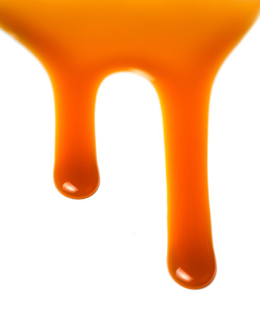 Flowing caramel sauce isolated on white background. Golden Butterscotch toffee caramel liquid 
の写真素材