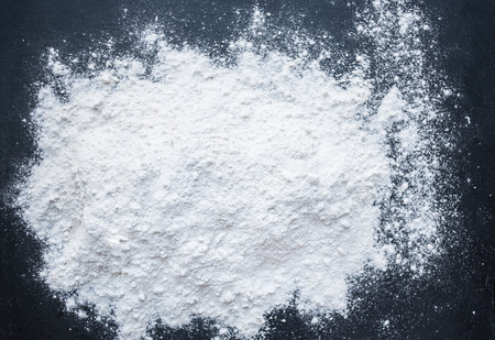White Flour powder on black background as dust splash clouds. Baking preparation, top view. Cooking...