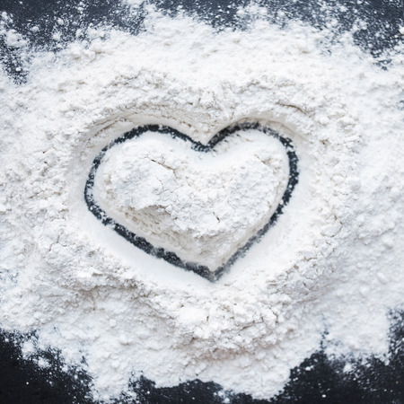 Valentine Day Concept idea image - Heart shape in a baking flour on black background. Cooking love recipe conceptの写真素材