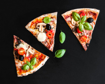 Slice of  Italian classic Pizza with salami, ham and bacon,  cheese, pepper and olives over  black ...