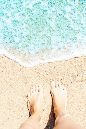 Soft wave of blue ocean on sandy beach Background with women feets, view from above. Tropical summer vacation concept.
の写真素材