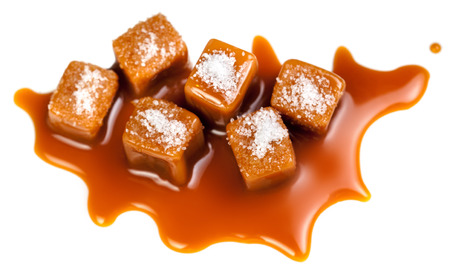 Salted Caramel candies pieces  and caramel sauce splashes solated on a white background. Toffee caramel candies close-up
の写真素材