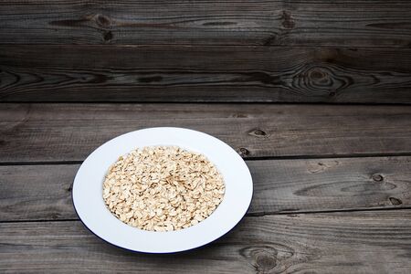 Oatmeal, rolled oats on rustic white wooden background.  Food Concept of healthy eating or vegan food. Healthy breakfast. Copyspaceの写真素材