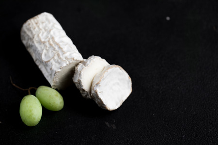 Stick of a goat cheese on black stone background. Fresh goat cheese with copy spaceの写真素材