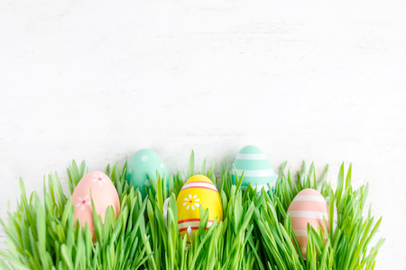 Easter background with row of colorful eggs hiding in  green grass, copy space. Top view.  Easter holiday decorationsの写真素材