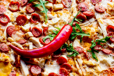  Cheese pepperoni pizza with chilli pepper and  delicious toppings  on a dark wooden background. Top view の写真素材
