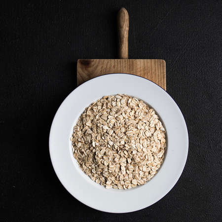 Oatmeal, rolled oats on black stone background.  Food Concept of healthy eating or vegan food. Healthy breakfast. Copyspaceの写真素材