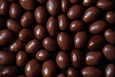 Chocolate candy textured background.  Dark brown chocolate round candies on black concrete...