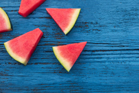 Watermelon fruit pieces  on a  blue rustic wood background, flat lay. Summer conceptの写真素材