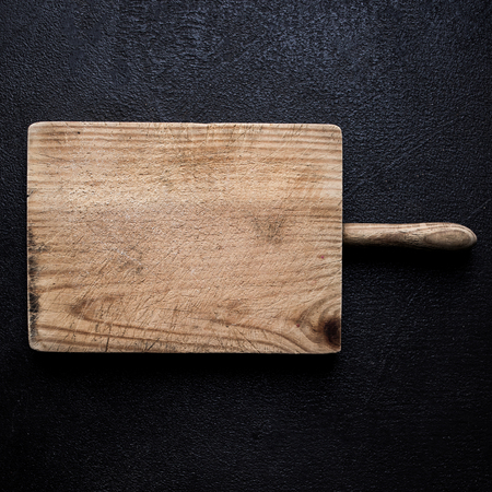 Old Chopping cutting board on black chalkboard  background. Empty Textured kitchen desk. Food...