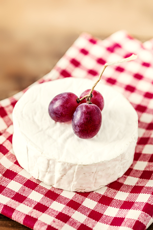 Cheese camembert on wooden desk, top view. Soft creamy cheese Brie with red grapeの写真素材