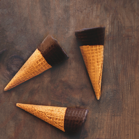 Ice cream cones pattern. Sweet Ice-cream cones with chocolate on wooden background, flat lay. Summer concept. Top view.の写真素材