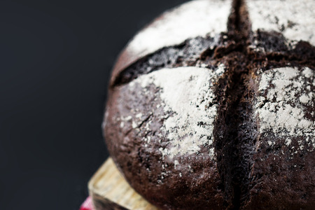 Rye bread on black background with copy space. Round Loaf of fresh baked dark bread on cutting board close upの写真素材