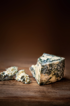 Blue cheese Gorgonzola on a rustic wooden background. Mold cheese with copyspace and dark backdropの写真素材