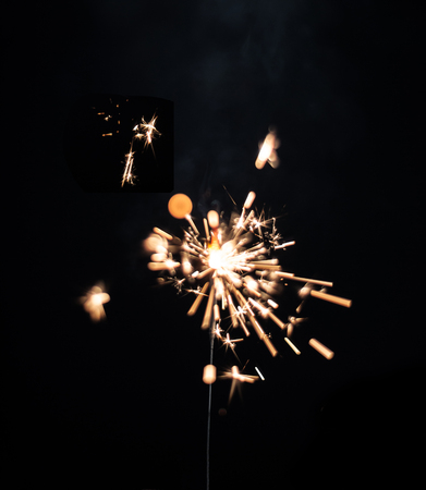 Christmas glittering sparklers over black background. Xmas festive decoration lighting element. Magic golden sparks lightsの写真素材