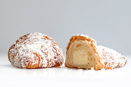 Freshly baked  croissant  cut in a half with coconut flakes  on white background close upの写真素材