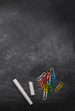 Back to school Background with paper clips and white chalk sticks on black board. School supplies for classes and lessons.  Copy space. Top viewの写真素材