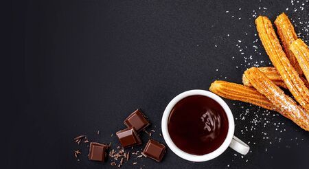 Churros with liquid chocolate. Churro - Fried dough pastry with sugar powder on black  background....