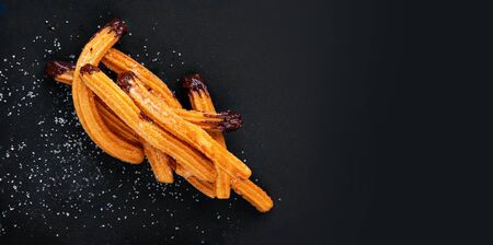 Traditional Churros with sugar and chocolate sauce on black background.  Churro - Fried dough pastryの写真素材