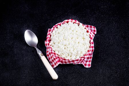 Homemade cottage cheese in a ceramic bowl on black  table. Healthy food. Fresh dairy products. Close...
