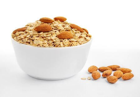 Oatmeal breakfast with almond nuts in bowl isolated on white background. Healthy food conceptの写真素材