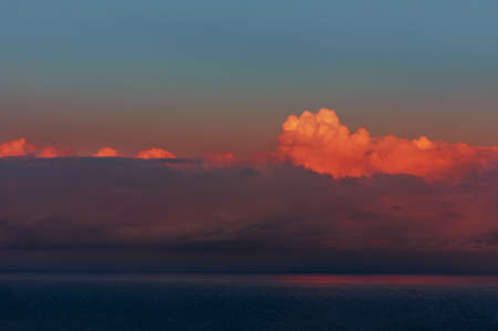 Dramatic sky over blue sea at sunset. Background of dark clouds before a thunderstorm