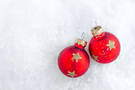 Christmas ornaments on snow with copy space. Glossy red balls top view.