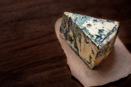 Blue cheese Gorgonzola on a dark wooden background. Mold cheese with copyspace. Fresh typical...
