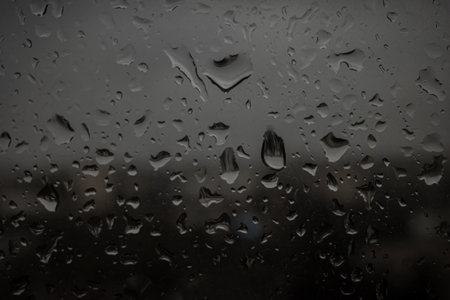 Drops of rain on a black dramatic window glass background. Autunm Rain, depression concept image