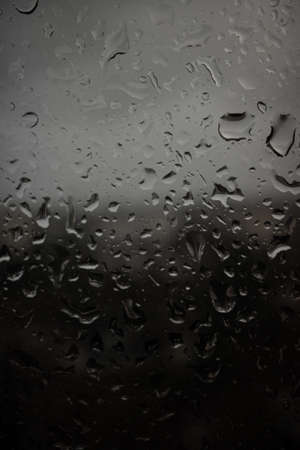 Drops of rain on a black dramatic window glass background. Autunm Rain, depression concept image