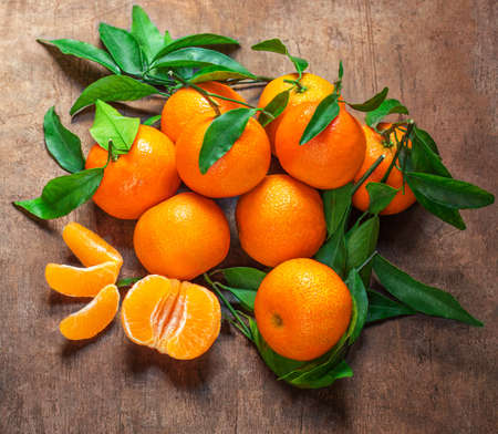 Mandarin oranges fruits or tangerines with leaves on a wooden table. Copyspace. Fresh picked mandarins Top view.の写真素材