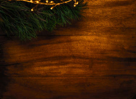 Christmas background with Christmas tree branches and golden lights, winter festive composition with copy space on dark wooden backdropの写真素材