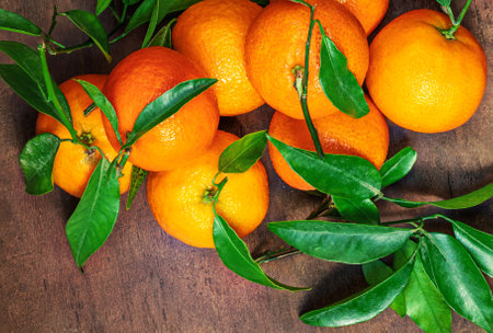 Sweet Mandarines oranges fruits or tangerines with green leaves on a wooden table. Copyspace. Fresh picked mandarins Top view.の写真素材