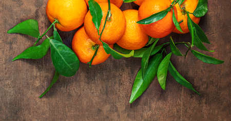 Mandarin oranges fruits or tangerines with leaves on a wooden table. Copyspace. Fresh picked mandarins Top view. Flat layの写真素材