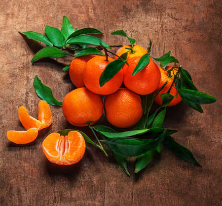 Mandarines oranges fruits or tangerines with green leaves on a dark wooden background. Copyspace.の写真素材