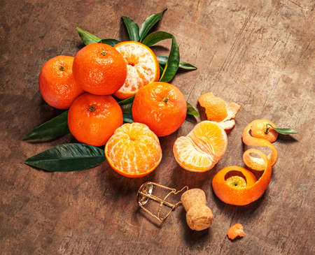 Mandarines oranges fruits (tangerines) with green leaves on a dark rustic wooden table. Copyspace.の写真素材