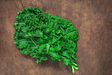 Kale leaf salad on wooden table. Fresh Kale closeup. Flat lay. Food vegan concept.の写真素材