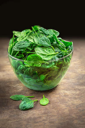 Spinach leaves in a bowl on wooden table. Fresh Spinach Closeup. copy spaceの写真素材