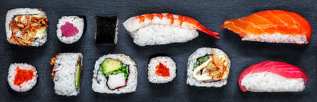 Sushi set on a black slate background. Japanese restaurant menu. Sushi with salmon, tuna and avocado. top view.の写真素材