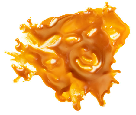 Liquid sweet melted caramel splash isolated on a white background. Toffee caramel sauce or maple syrup swirl top view. flat layの写真素材