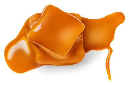 Caramel candies and flowing caramel sauce isolated on a white background. Pieces of toffee candies close upの写真素材